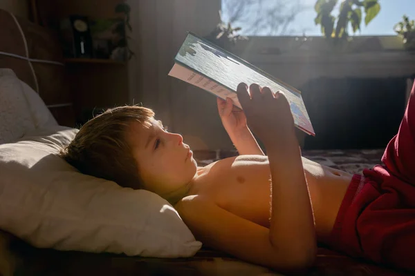 Schattig Kind Jongen Liggend Bed Met Boek Lezen Ochtend Zonnig — Stockfoto