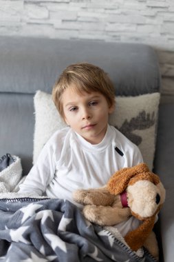 Hasta çocuk, küçük çocuk ateşler içinde yatağında yatıyor, evde dinleniyor.