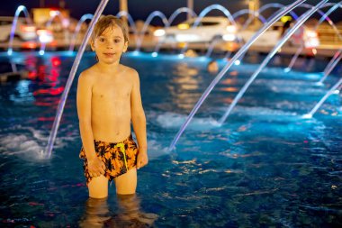 Tatlı çocuk, Tel Aviv 'deki çeşmede suyla oynuyor, ışıklar ve renkler.