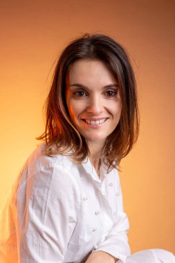 Stüdyoda gülümseyen orta yaşlı beyaz bir kadının portresi.