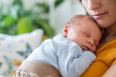 Genç anne, şefkatle kucağında yeni doğmuş bebeğini, yakın bir portre