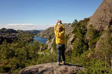 Happy people, enjoying amazing views in South Norway coastline, fjords, lakes, beautiful nature. Kids and adults traveling in Norway summertime