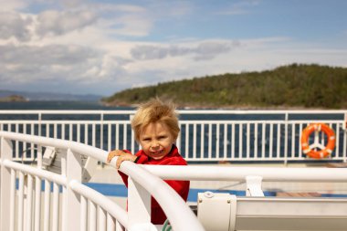Children, experience ride with ferry on a fjord, strong wind on the deck of the ferry on a sunny day