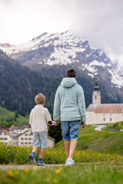 Çocuklar, İsviçre Alpleri 'ndeki erkek kardeşler. İlkbahar günü evcil köpekleri ile geziyorlar ve doğanın tadını çıkarıyorlar.