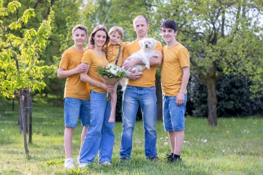 Parkta çocuklu ve evcil köpekli mutlu bir aile, gün batımında birlikte eğleniyorlar.