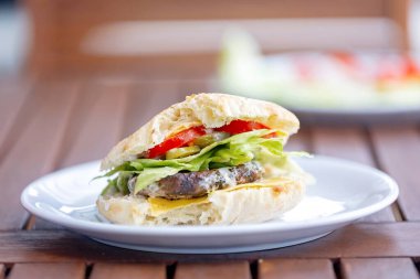 Tatlı küçük çocuk, oğlum, sandviç yiyor, kış bahçesinde salatalı burger yiyor.