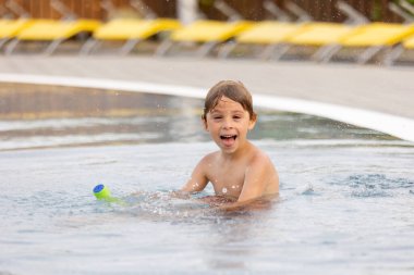 Tatlı bir çocuk, su parkında bir çocuk, kardeşleriyle yaz tatilinde eğleniyor.