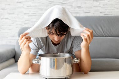 Genç bir çocuk, çocuk, evde buhar solunumu yapıyor burun deliklerini yatıştırmak ve açmak için, eski doğal yöntem