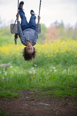 Tatlı çocuk, preteen çocuk, yağlı tohum alan yakın bir ağaçta bir ahşap salıncak üzerinde sallanan