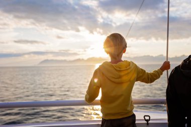 Millet, Bodo ve Lofoten Moskenesoya arasındaki feribot yolculuğunun tadını çıkarın. Yaz mevsimi, gün batımında çocuk ve yetişkinler feribotta.