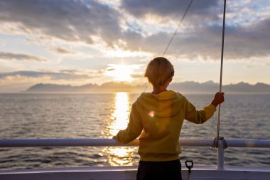 Millet, Bodo ve Lofoten Moskenesoya arasındaki feribot yolculuğunun tadını çıkarın. Yaz mevsimi, gün batımında çocuk ve yetişkinler feribotta.