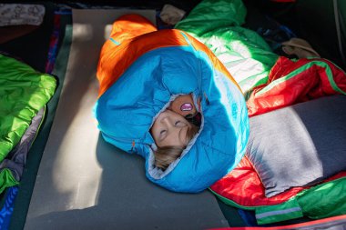 Tatlı bebek sarışın çocuk, çocuk ve evcil köpek, Norveç 'te tatilde bir çadırda uyku tulumunda uyuyor, vahşi doğada kamp yapıyor.