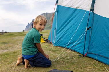 Kuzey Norveç, Senja 'daki Ersfjord plajında kamp yaparken sahilde yemek yiyen mutlu çocuklar. Çocuklar dışarıda öğle yemeği yiyor.