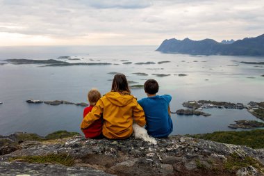 Çocuklu ve evcil hayvanlı aile, çocuklar ve yetişkinler Norveç 'in Senja adasında Sukkertoppen yolunda yürüyüş yapıyorlar.