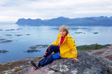 Family with children and pet, kids and adults hiking Sukkertoppen trail on Senja island, Norway clipart