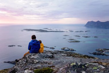 Çocuklu ve evcil hayvanlı aile, çocuklar ve yetişkinler Norveç 'in Senja adasında Sukkertoppen yolunda yürüyüş yapıyorlar.