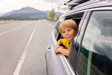 Tatlı bir çocuk, pencereden dışarı bakıyor, Lofoten, Kuzey Norveç 'te güzel bir manzaraya bakıyor.
