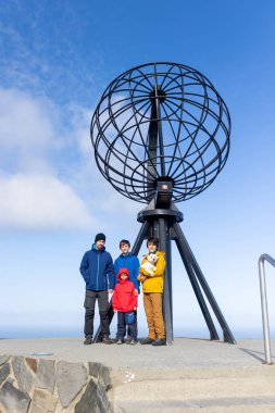 Çocuklu ve evcil köpekli bir aile yaz tatilinde Nordkapp 'ı ziyaret ediyor. Çocuklar ve yetişkinler Kuzey Burnu 'ndaki ünlü dünyayı ziyaret ediyorlar.