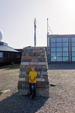 Family with children and pet dog, visiting Nordkapp during the summer holiday. Kids and adult visiting the famous globe on North Cape clipart