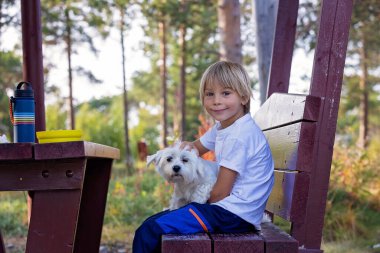 Cute blond child, eating lunch in a campside along the road in Norway, summertime clipart