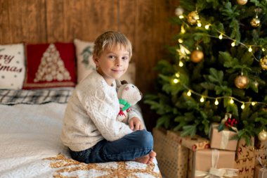 Tatlı sarışın çocuk, çocuk, Noel 'i evde kutluyor, tatiller için dekore edilmiş oda, çocuk kitapları okuyor ve oyun oynuyor.