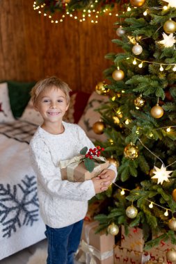 Tatlı sarışın çocuk, çocuk, Noel 'i evde kutluyor, tatiller için dekore edilmiş oda, çocuk kitapları okuyor ve oyun oynuyor.