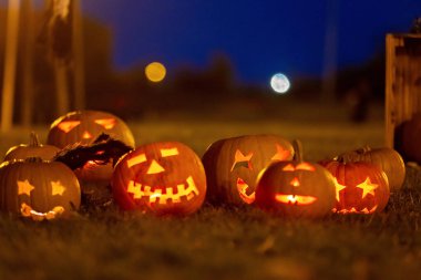 Parkta Cadılar Bayramı kostümlü iki çocuk mum ve dekorasyonla balkabağı oyup oynuyorlar.