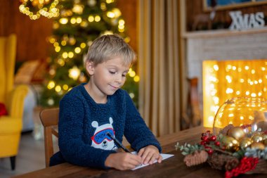 Tatlı sarışın çocuk, çocuk, Noel 'i evde kutluyor, tatiller için dekore edilmiş oda, çocuk kitapları okuyor ve oyun oynuyor.