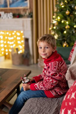 Tatlı sarışın çocuk, çocuk, Noel 'i evde kutluyor, tatiller için dekore edilmiş oda, çocuk kitapları okuyor ve oyun oynuyor.