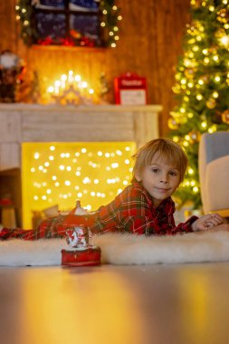 Güzel sarışın çocuk, genç okul çocuğu, süslü bir evde okul için ödev yazıyor, süt içiyor ve kurabiye yiyor. Işıklar ve örgü oyuncaklar