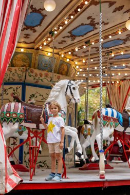 Tatlı sarışın çocuk, Atlıkarınca Yuvarlak 'a gidiyor, çocuk atlıkarınca parkında oynuyor, yaz zamanı.