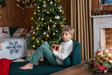 Tatlı sarışın çocuk, tatlı çocuk, Noel 'de Noel oyuncaklarıyla oynayan, Noel için güzel dekore edilmiş ev, ışıklarla dolu rahat bir yer.