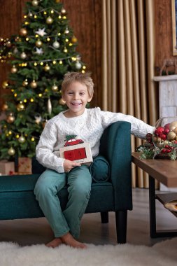 Tatlı sarışın çocuk, tatlı çocuk, Noel 'de Noel oyuncaklarıyla oynayan, Noel için güzel dekore edilmiş ev, ışıklarla dolu rahat bir yer.