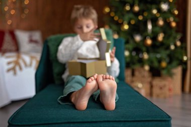 Tatlı sarışın çocuk, tatlı çocuk, Noel 'de Noel oyuncaklarıyla oynayan, Noel için güzel dekore edilmiş ev, ışıklarla dolu rahat bir yer.