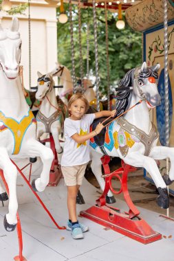 Tatlı sarışın çocuk, Atlıkarınca Yuvarlak 'a gidiyor, çocuk atlıkarınca parkında oynuyor, yaz zamanı.