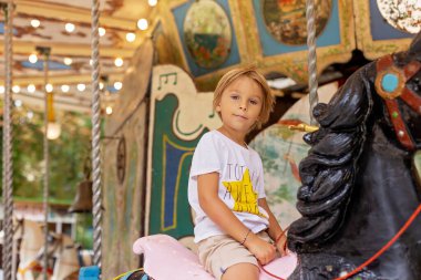 Tatlı sarışın çocuk, Atlıkarınca Yuvarlak 'a gidiyor, çocuk atlıkarınca parkında oynuyor, yaz zamanı.