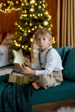 Tatlı sarışın çocuk, tatlı çocuk, Noel 'de Noel oyuncaklarıyla oynayan, Noel için güzel dekore edilmiş ev, ışıklarla dolu rahat bir yer.