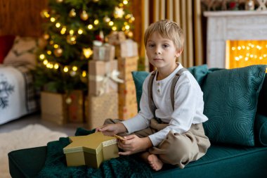 Tatlı sarışın çocuk, tatlı çocuk, Noel 'de Noel oyuncaklarıyla oynayan, Noel için güzel dekore edilmiş ev, ışıklarla dolu rahat bir yer.