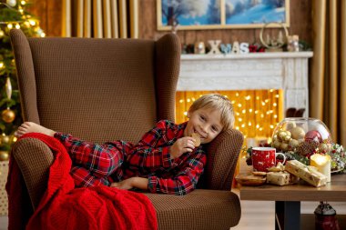 Tatlı sarışın çocuk, tatlı çocuk, Noel 'de Noel oyuncaklarıyla oynayan, Noel için güzel dekore edilmiş ev, ışıklarla dolu rahat bir yer.