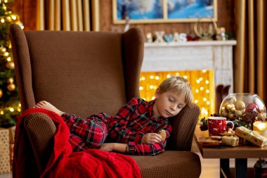 Tatlı sarışın çocuk, tatlı çocuk, Noel 'de Noel oyuncaklarıyla oynayan, Noel için güzel dekore edilmiş ev, ışıklarla dolu rahat bir yer.