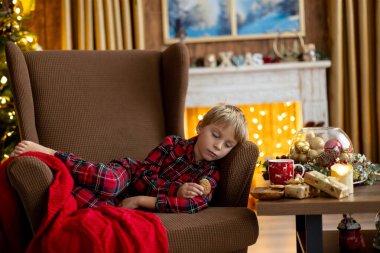 Tatlı sarışın çocuk, tatlı çocuk, Noel 'de Noel oyuncaklarıyla oynayan, Noel için güzel dekore edilmiş ev, ışıklarla dolu rahat bir yer.