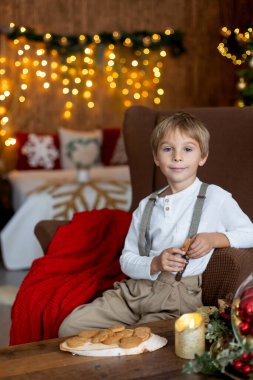 Tatlı sarışın çocuk, tatlı çocuk, Noel 'de Noel oyuncaklarıyla oynayan, Noel için güzel dekore edilmiş ev, ışıklarla dolu rahat bir yer.
