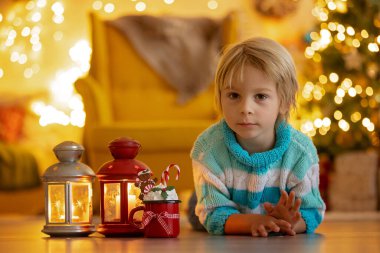 Tatlı çocuk, oğlum, Noel için süslü bir odada sarı bir koltukta oturuyor, rahat bir yer.