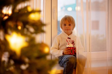 Tatlı çocuk, oğlum, Noel için süslü bir odada sarı bir koltukta oturuyor, rahat bir yer.