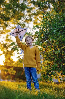 Güzel sarışın çocuk, oğlum, sonbaharda bir tarlada uçurtmayla oynuyor.