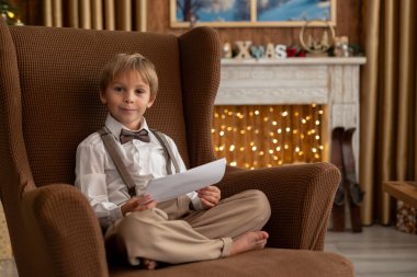 Tatlı sarışın çocuk, tatlı çocuk, Noel 'de Noel oyuncaklarıyla oynayan, Noel için güzel dekore edilmiş ev, ışıklarla dolu rahat bir yer.