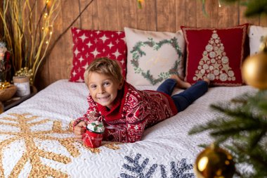 Tatlı sarışın çocuk, çocuk, Noel 'i evde kutluyor, tatiller için dekore edilmiş oda, çocuk kitapları okuyor ve oyun oynuyor.