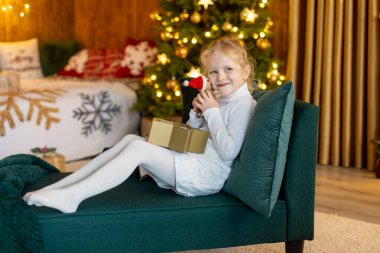 Mutlu şirin çocuk, Noel 'deki kız, güzel dekore edilmiş bir evde Noel tatilinin tadını çıkarıyor. 