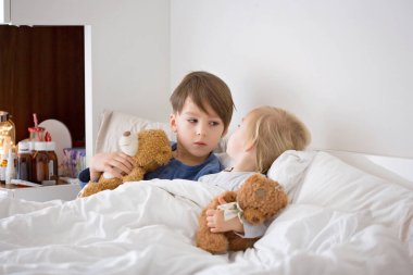 Hasta çocuklar, küçük çocuklar ve büyük çocuklar, kardeşler, yatakta ateşler içinde yatıyorlar, dinleniyorlar.