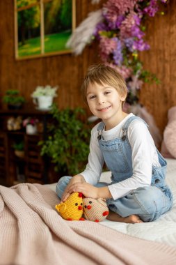 Mutlu güzel çocuk, çocuk, küçük güzel örgü piliçle oynuyor, bahar çiçekleri ve bahar arka planında bisiklet.
